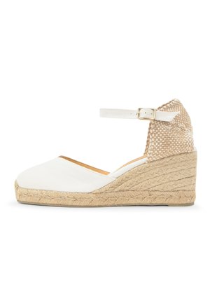 Biela klinová espadrilová obuv s popruhom okolo členku, béžovým pleteným zadným dielom a opletenou jútovou podrážkou.