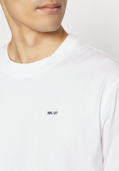 Weißes Baumwoll-T-Shirt mit Rundhalsausschnitt und kleinem schwarzen gestickten "NN. 07" Logo auf der linken Brustseite.