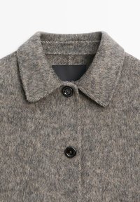 Wool coat in grey tones with a soft texture, featuring a classic collar and a black button. Label inside is partially visible.