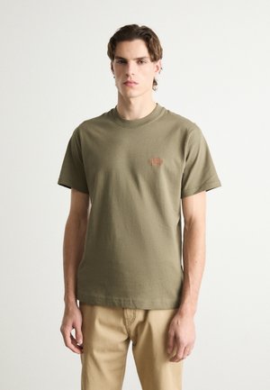 Olive green cotton T-shirt with short sleeves, round neckline, and small embroidered logo on the chest. Textured fabric with a relaxed fit.