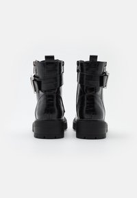 Černé kotníkové boty s krokodýlím textura, zapínání na zip, dvě nastavitelné přezky a robustní gumová podrážka.