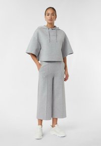 Gray cropped hoodie with wide sleeves, featuring a front pocket and drawstrings. Paired with matching wide-leg pants and white sneakers.