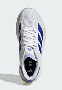 Zapatilla deportiva blanca con parte superior de malla transpirable, rayas azules, cuello acolchado y plantilla Ortholite. Cuenta con una suela exterior de goma texturizada.
