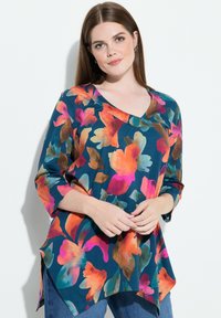 Top con scollo a V e maniche a tre quarti realizzato in tessuto liscio. Verde petrolio scuro con stampa floreale vivace nei toni del rosa, arancione e verde. Orlo asimmetrico.