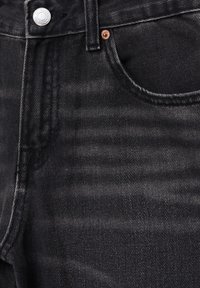 Schwarze Jeans aus Denim mit strukturiertem Finish, ausgestattet mit einem Metallknopfverschluss, Kupfernieten und einem klassischen Taschendesign.