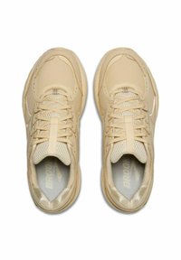 Zapatillas deportivas beige con parte superior de malla y cuero, punta redonda, lengüeta acolchada y cordones planos. Presenta un logotipo sutil en el forro interior.