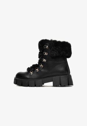 Čierne kožené členkové topánky s umelou kožušinou okolo členka, s kovovými očkami a háčikmi, masívna podrážka s hlbokými drážkami pre lepšiu priľnavosť.