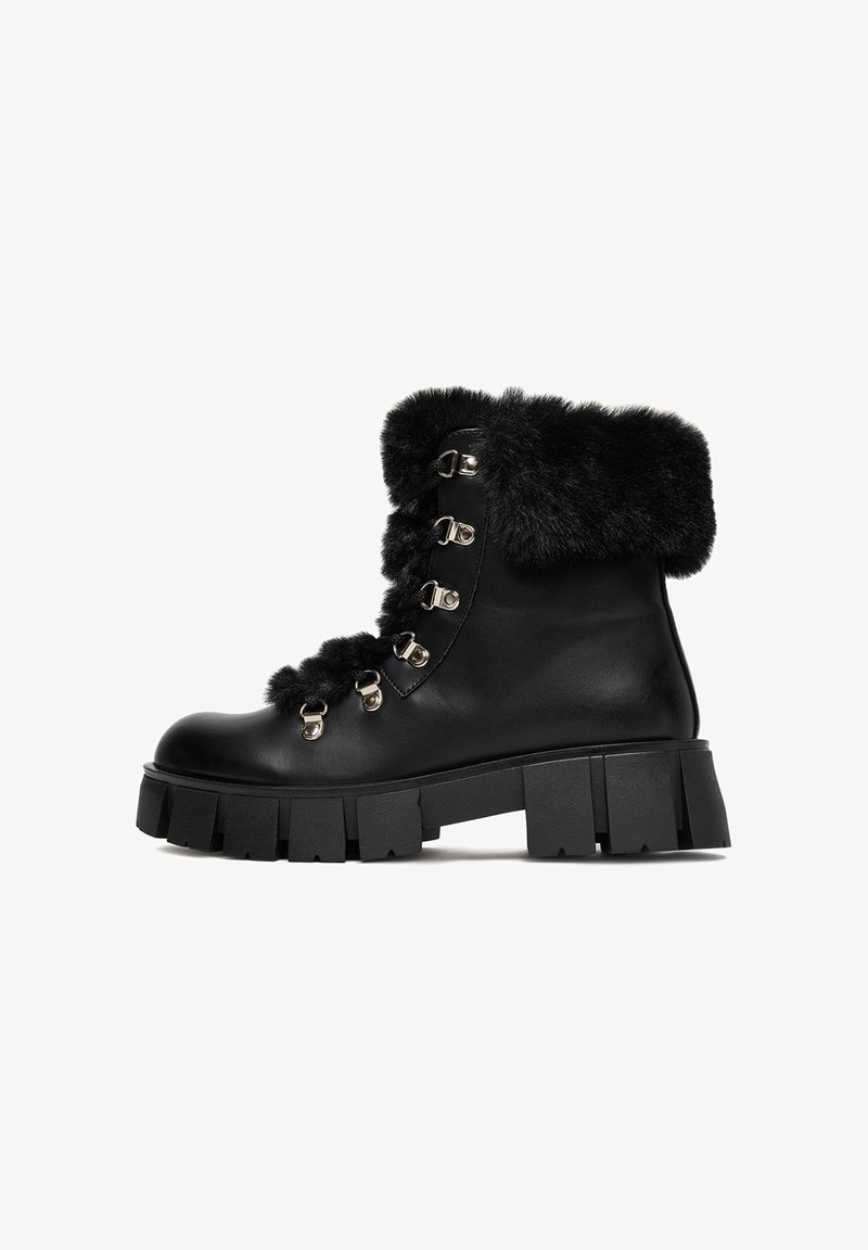 Černé kožené kotníkové boty s umělou kožešinou, obsahující kovové očky a háčky, robustní podrážka s hlubokými drážkami pro lepší trakci.