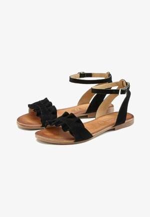 Black suede sandals with ruffled straps, ankle buckle, and a flat brown sole. Soft texture and simple design. Suitable for casual wear.