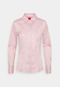 Blusa rosa a maniche lunghe con design aderente, realizzata in tessuto liscio, caratterizzata da un colletto appuntito e chiusura frontale con bottoni.