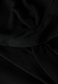 Tissu tricoté noir avec une finition texturée, présentant un détail de design tordu. Lisse et légèrement élastique, avec des coutures visibles.