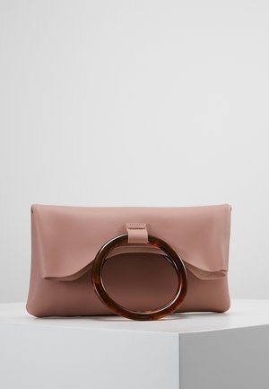 Pochette en cuir rose avec une grande anse circulaire en écaille de tortue reposant sur une plateforme blanche contre un fond gris clair.