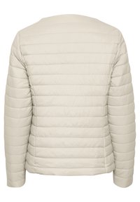 Jasno beżowa pikowana kurtka z poziomym przeszyciem, z długimi rękawami i zaokrąglonym dekoltem. Gładka, lekko błyszcząca faktura tkaniny.