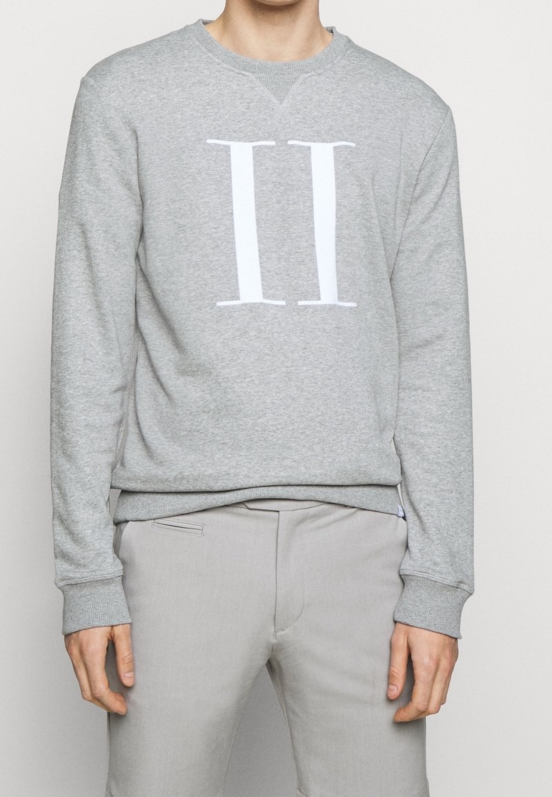 Szara bluza wykonana z miękkiego materiału, z wyraźnym białym nadrukiem "II" na przodzie. Mankiety i pas ze ściągaczem.
