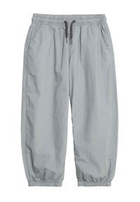 Lys grå joggerbukser lavet af blødt stof, med elastisk talje og snoretræk, samt elastiske manchetter ved anklerne.