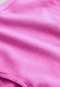 Tessuto di cotone rosa con una superficie liscia, caratterizzato da una leggera lucentezza e morbide pieghe. Il bordo presenta un dettaglio di cucitura nel collo.