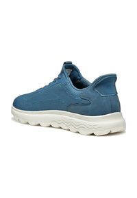 Scarpa sportiva blu con tomaia testurizzata e dettagli lisci. Presenta una suola bianca spessa e ondulata e un design con lacci.