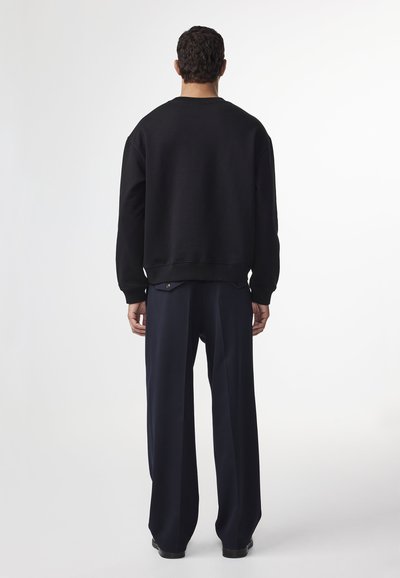 Schwarzer Sweatshirt mit Rundhalsausschnitt und gerippten Bündchen, kombiniert mit locker sitzenden, marineblauen Hosen. Glatte Textur, minimalistisches Design.