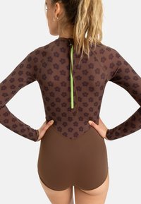 Maillot de bain long à manches marron avec un motif floral sur la partie supérieure, section inférieure marron uni, et une fermeture éclair verte au dos.