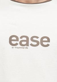 Maglietta bianca in cotone con scollo marrone chiaro e testo audace con la scritta "ease" sopra "lo-fi summer life". Tessuto morbido, design casual.