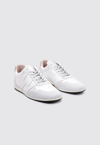 Zapatillas deportivas blancas con un upper texturizado, que cuentan con una puntera lisa y acentos plateados, cordones grises y un interior acolchado.