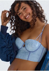 Svetlo modra denim corset-stil braletka z tankimi naramnicami, detajlom v obliki ključavnice in strukturiranimi skodelicami, v kombinaciji s temno modro napihnjeno jakno.