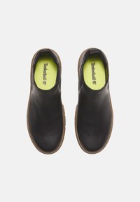 Scarpe slip-on nere in pelle con design a punta rotonda, suola in gomma e interno verde lime con il logo Timberland.