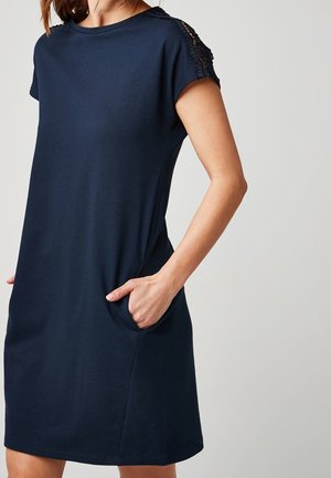 Granatowa sukienka z miękkiej tkaniny, z okrągłym dekoltem, krótkimi rękawami z koronkowymi zdobieniami oraz bocznymi kieszeniami.