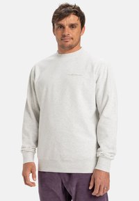 Světle šedá fleecová mikina s kulatým výstřihem, žebrovanými manžetami a spodním lemem. Discretní vyšívané logo na hrudi. Texturovaná látka s měkkým povrchem.