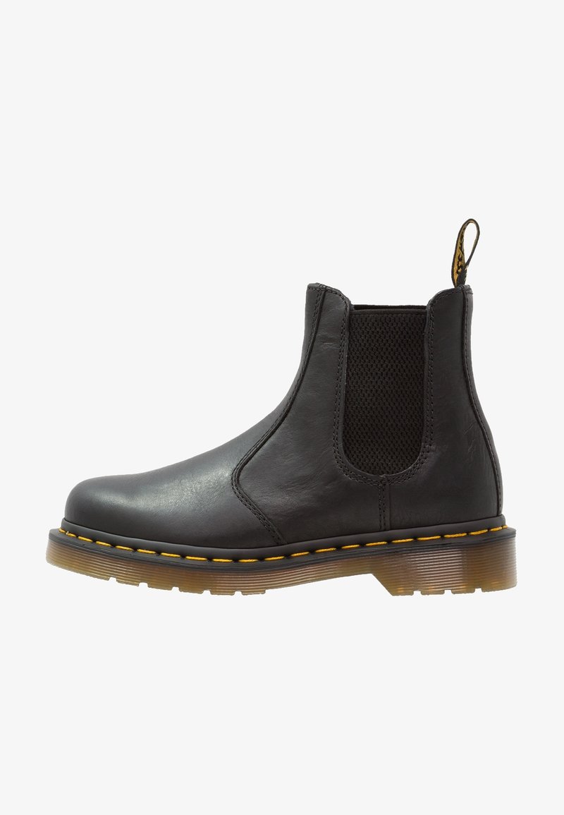 Bottines Chelsea en cuir noir avec panneaux latéraux élastiques, couture jaune le long de la semelle, semelle translucide crantée et bandeau en tissu à l'arrière.