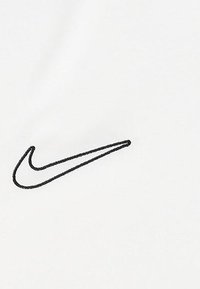 Il tessuto bianco presenta un prominente logo Swoosh Nike ricamato in nero, una texture liscia e un design minimalista.