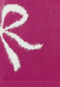 Zbliżenie na magentową dzianinę z puszystym białym wzorem w kokardki po lewej stronie.