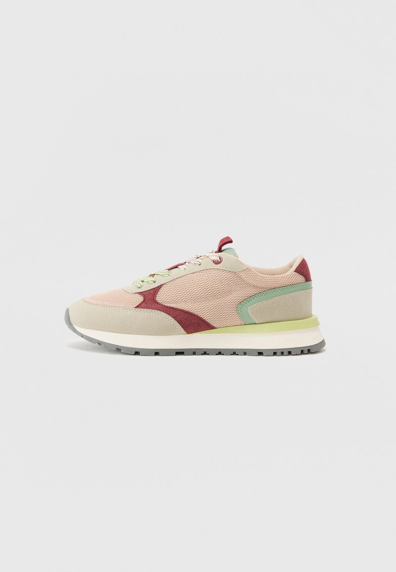 Light pink and beige sneaker with red and green accents, mesh fabric, padded collar, and a textured rubber sole. Features flat laces.