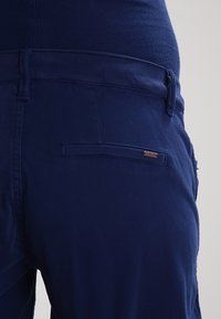 Granatowe bawełniane spodnie o prostym kroju, z tylną kieszenią z przeszytym akcentem oraz subtelną teksturą.