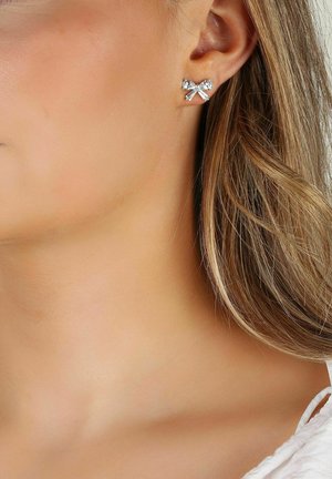 Silverfärgade stiftörhängen formade som en rosett med klara rhinestones, med en polerad yta och en enkel, elegant design.