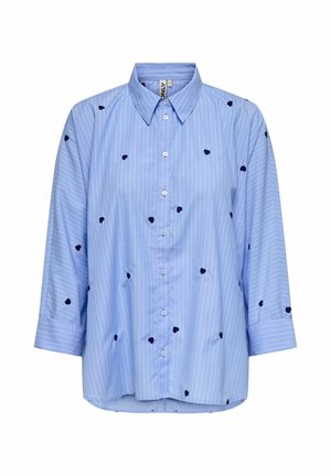 Camisa de botones azul claro con rayas verticales blancas, con bordado en forma de corazón en color marino. Corte relajado y mangas de tres cuartos.