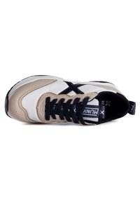 Beige and white sneaker with black accents, featuring a leather and mesh upper, round toe, flat black laces, and a textured sole.