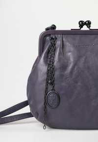 Borsa in pelle viola dalla forma arrotondata, con un accento in catena e un ciondolo circolare. Texture liscia e chiusura a cornice superiore.