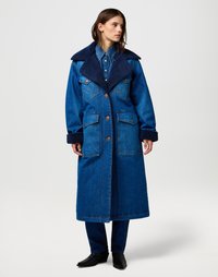 Denimjack in een diepe blauwe tint, met een grote marineblauwe schapenvacht kraag, knoopsluiting en dubbele voorzakken. Vergezeld van bijpassende broeken.