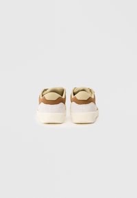 Et par beige og brune Nike SB sneakers vist fra baksiden på en enkel hvit bakgrunn.