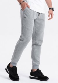 Grijze sweatpants in een tapered ontwerp, met elastische boorden, schuine zijzakken en een tailleband met trekkoord. Gecombineerd met zwarte sneakers.
