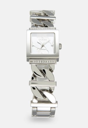 Montre-bracelet Guess ton argent avec un cadran carré, des accents en cristal au-dessus et au-dessous du cadran, et un bracelet à maillons épais.