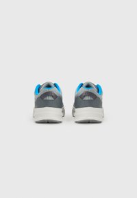Chaussures de sport grises avec une tige texturée, des accents bleus et une semelle intermédiaire blanche. Le design présente une pointe arrondie et une zone de talon rembourrée.