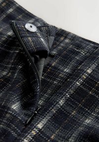 Námořnicky modré kárované kalhoty mají zipový klín se zapínáním na druk. Tkanina má měkkou texturu s světlými a tmavými károvanými vzory.