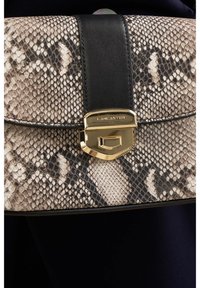 Handtas met een slangenhuidpatroon, voorzien van een zwarte leren schouderband, een gouden sluiting en een rechthoekige vorm. Getextureerd materiaal met gedetailleerde accenten.