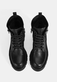 Bottines en cuir noir avec une finition texturée, dotées de lacets et de fermetures éclair sur les côtés, semelles en caoutchouc et d'une languette à l'arrière.