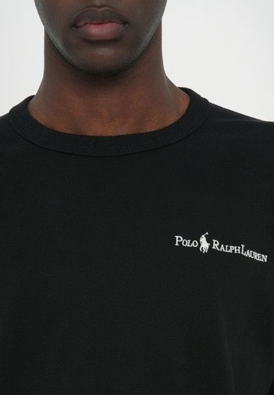 Tricou din bumbac negru cu guler rotund, având un logo brodat alb "Polo Ralph Lauren" pe partea stângă a pieptului.