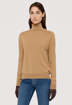 Pull à col roulé beige avec un design ajusté, des poignets et un ourlet côtelés, porté avec des gants marron foncé. Texture semblable à du coton et épaules sans couture.