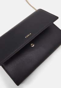 Czarny portfel ze skóry o fakturowanym wykończeniu, z logo marki w złotym odcieniu, zapięciem na zatrzask i paskiem na łańcuszku dla wszechstronności.