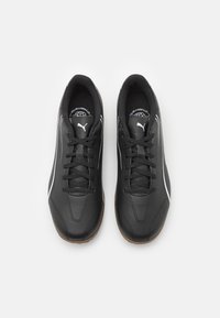 Černé sportovní boty s hladkým koženým povrchem, bílými akcenty, zaoblenou špičkou a texturovanou gumovou podrážkou. Obsahují tradiční šněrovací design.